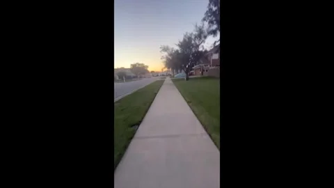 First-Person Point of View Walking Down a Concrete Suburban Sidewalk at Dusk Stock Footage 341293812