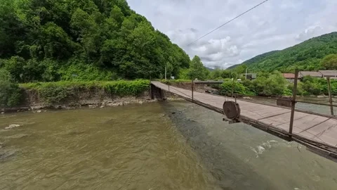 First-person POV perspective looking across a narrow wooden suspension bridge Vídeo Stock 346182360