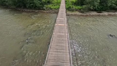 First-person POV perspective walking across a narrow wooden suspension Vídeo Stock 346182321