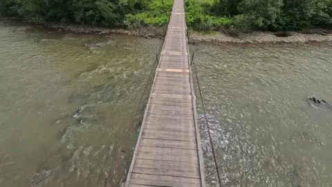 First-person POV perspective walking across a narrow wooden suspension Vídeo Stock 346182359