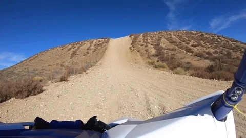 First person racing uphill in UTV through desert landscape to motocross Stock Footage 98703243