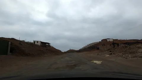First person view from a car going up a sloppy track and broken houses and Vidéo 155776094