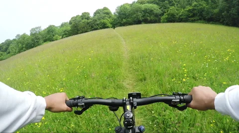 First person view of a cyclist speeding through a path in a lush green field Free Stock Footage 51037895