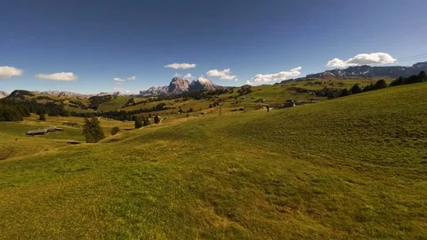 First person view flying over a lush green meadow towards mountains Stock Footage 327333658