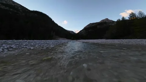 First person view flying over a mountain stream at sunset Stock Footage 327333688