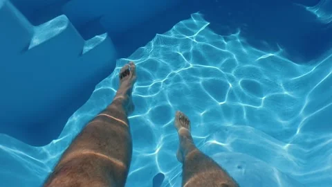 First person view of legs in clear blue water of swimming pool sunlight ref.. Stock Footage 334901848
