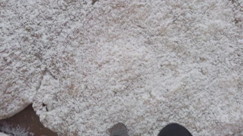 First-person view of legs of a man in black suede sneakers walking on snow floes Stock Footage 309021017