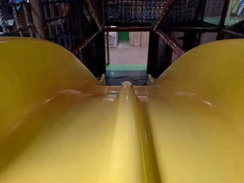 First-person view looking down a bright yellow double slide Fotos Stock
