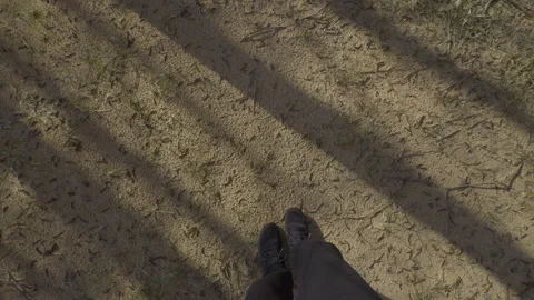 First person view from a man in black sneakers and jeans on the sand and a green Stock Footage 309531647