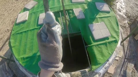 First person view of a man drawing water of an old pit in the countryside. Fa Stock Footage 136057877