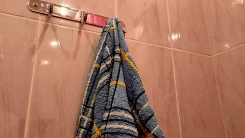 First person view a man hangs a colored blue and white towel in the bathroom. Stock Footage 143368870
