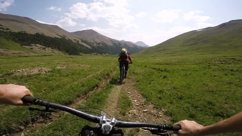 First Person View Of A Man Mountain Biking Behind A Woman In The Alpine Video stock 102453718