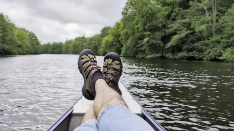 First person view of a man relaxing with his feet up on the bow of a canoe Video stock 337809880