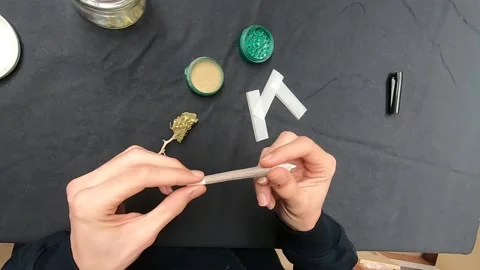 First person view of man rolling and smoking a joint of marijuana. Marijuana Stock Footage 136042354