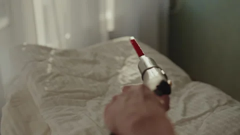 First-person view of man steaming fresh white blanket on bed in bright bedroom Stock Footage 304878739