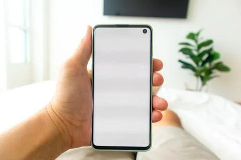 First person view of man using smartphone while on the bed. Foto stock
