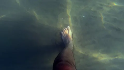 First person view of man walking underwater on sandy seabed Stockbeeldmateriaal 279898990