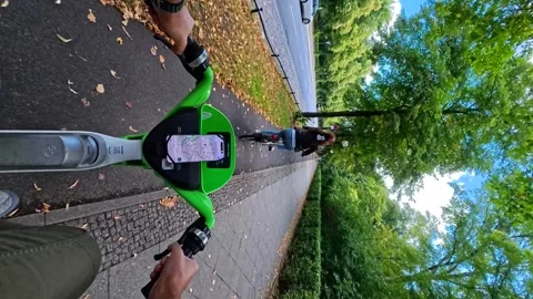 A first-person view of riding a lime electric scooter on a paved path in Berlin Stock Footage 326024641