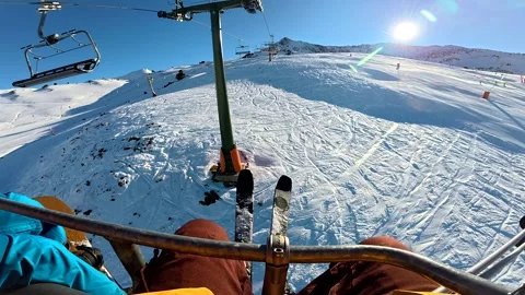 First person view riding a ski lift uphill over snowy slopes Stock Footage 323353560
