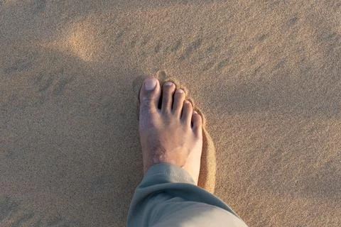 First person view of a single foot standing on golden sand dunes. Stock Photos
