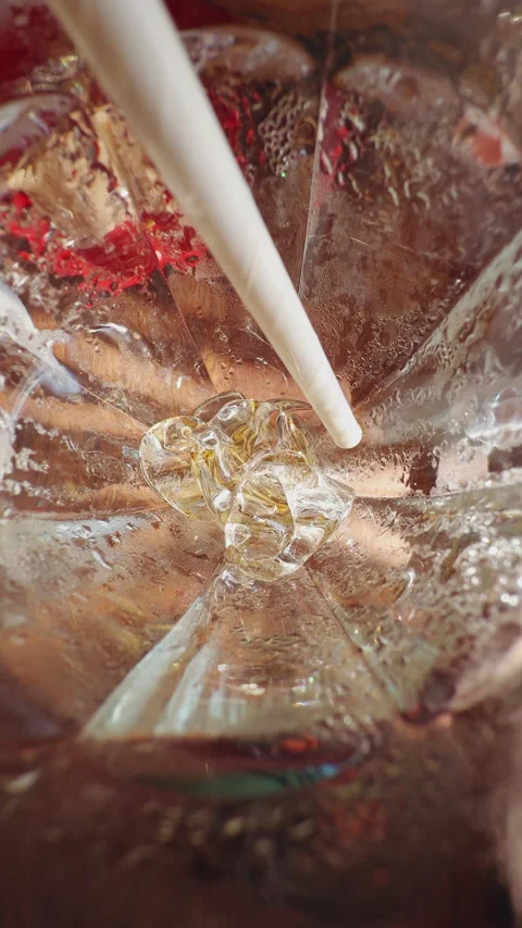 First Person View Stirring Ice Cubes With Straw Inside Glass of Cola, Macro Clos Stockbeeldmateriaal 336815147
