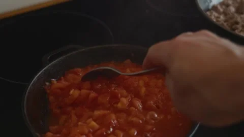 First-person view stirring tomatoes in eco cast iron skillet Stock Footage 315243294
