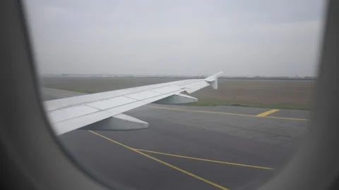 First-person view through window on wing of airplane taxiing down runway Stock Footage 243305395