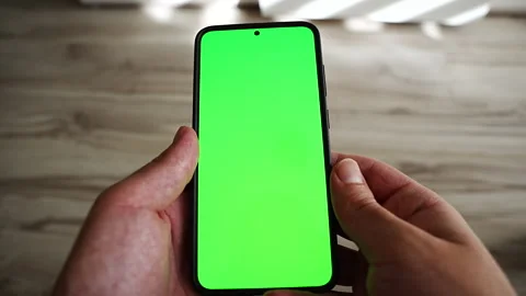 First person view of two hands holding a smartphone with a green screen display Video stock 347510959
