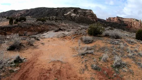 First person view of walking down red dirt path towards stream bed. Stock Footage 105143933