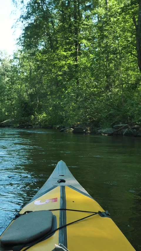 First person view of a yellow inflatable kayak floating down a gentle river Stock Footage 343775000