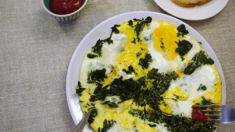 First perspective view. The process of eating scrambled eggs with spinach. Stock Photos