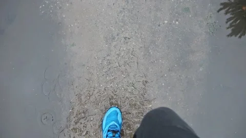 First perspective view of shoes wading in a puddle, the water spilling out at Video stock 211885405