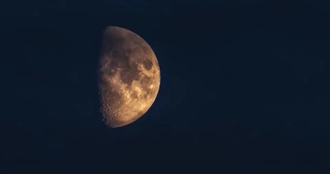 First quarter moon rising through dark blue twilight clouds time lapse Stock Footage 340413353