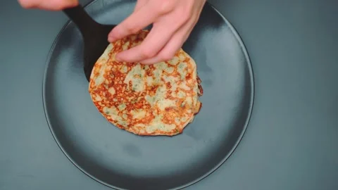 The first ready pancake is placed on a plate Stock-Footage 249559965