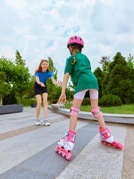 First ride. Girl learning roller skating with guidance in park 스톡 사진
