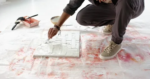 At first second, Hispanic male artist is scooping medium and smoothing canvas in Stock Footage 335269027