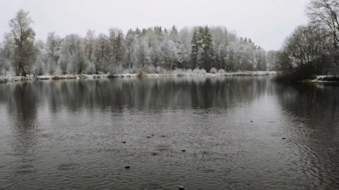 The first snow that falls on a not-yet-frozen lake Stock Footage 224486912