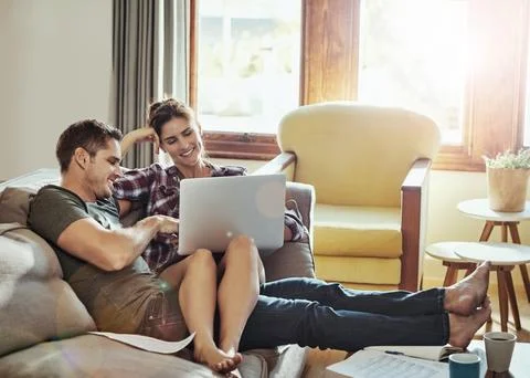 First some home admin then some relaxation. a young couple using a laptop and Stock Photos
