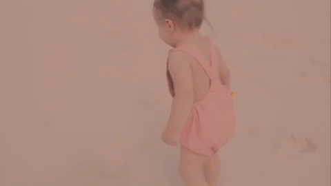 A first step of baby at the sand beach. A little girl walks the sand 動画素材 73909629