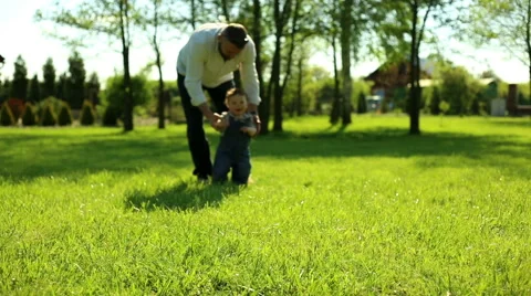 First steps baby with father in yard in at the village Stock Footage 63640989