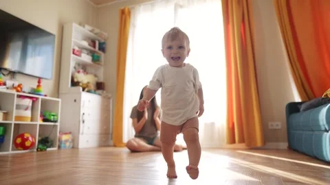 The first steps baby of learning to walk in home. Child toddler family concept Stock Footage 282510488