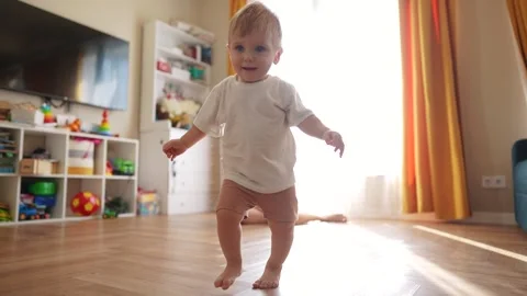 The first steps baby of learning to walk in home. Child toddler family concept Video stock 293507948