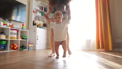 The first steps baby of learning to walk in home. Child toddler family concept Video stock 293508235