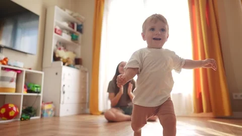 The first steps baby of learning to walk in home. Child toddler family concept Stock Footage 319537745