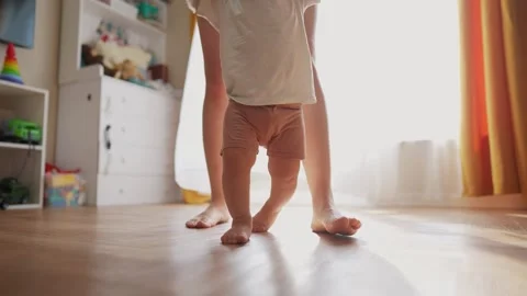 The first steps baby of learning to walk in home. Child toddler family concept Stock Footage 319538070