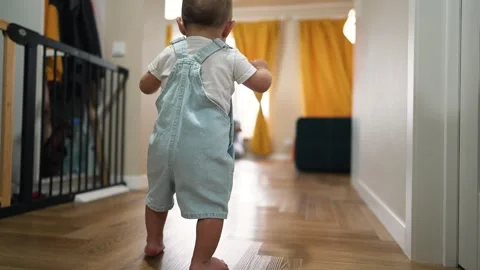 First steps. baby takes first steps at home on the floor. Child learns to walk Stock Footage 246580870