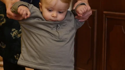 First steps of cute baby boy with mother hands support indoors Stock Footage 83241925