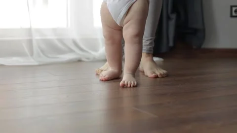 The first steps. A small child learns to walk holding his mother's hands Stock Footage