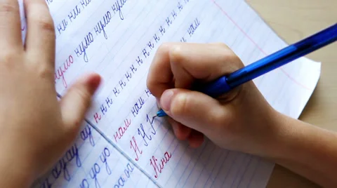 First steps in writing: little boy writes letters in diagonal lined notebook Stock Footage 33045709