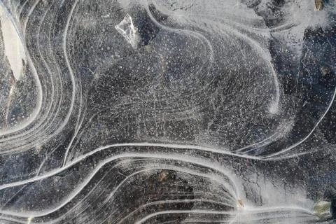 The first thin crust of ice on a puddle transparent and delicate. Texture, th Stock Photos